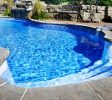 Residential inground swimming pool in backyard with waterfall and hot tub