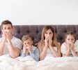 Family suffering from cold in bed at home