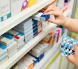 Pharmacist holding medicine box and capsule pack in pharmacy drugstore.