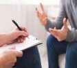 Psychotherapist writing notes, giving diagnosis to emotional man